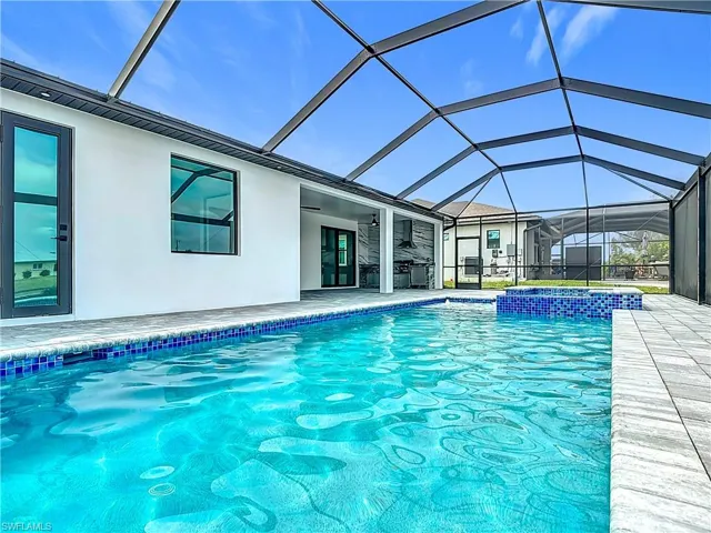 View of swimming pool with a patio area, a pool with connected hot tub, and glass enclosure