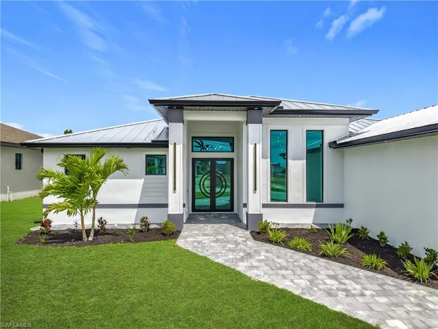 Doorway to property featuring a standing seam roof, metal roof, stucco siding, and a lawn