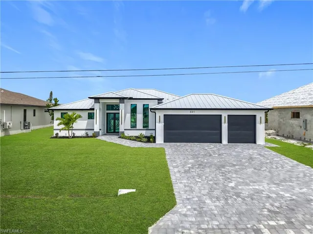 View of front facade featuring a front lawn, decorative driveway, metal roof, and a standing seam roof