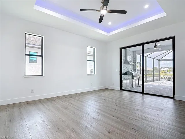Empty room featuring a tray ceiling, baseboards, and ceiling fan