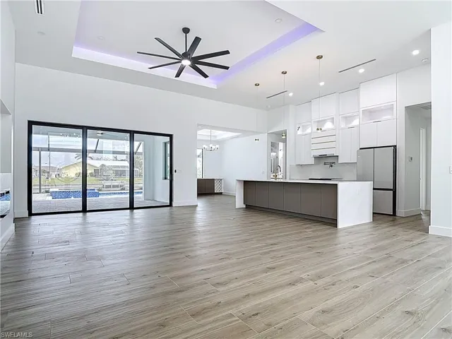 Kitchen featuring open floor plan, freestanding refrigerator, a raised ceiling, and modern cabinets