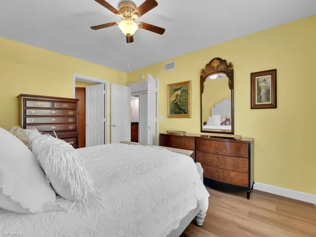 Bedroom with light wood finished floors, baseboards, visible vents, and ceiling fan