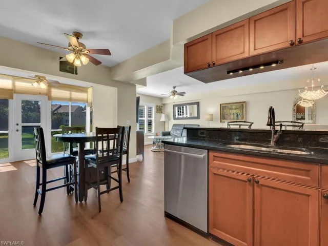 Kitchen with ceiling fan, a sink, light wood-style floors, stainless steel dishwasher, and brown cabinetry
