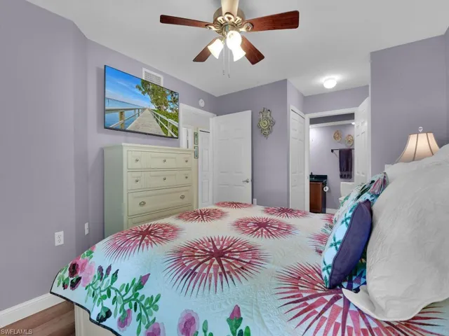 Bedroom featuring visible vents, ensuite bathroom, a ceiling fan, wood finished floors, and baseboards