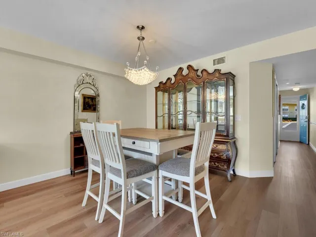 Dining space with a notable chandelier, baseboards, visible vents, and wood finished floors