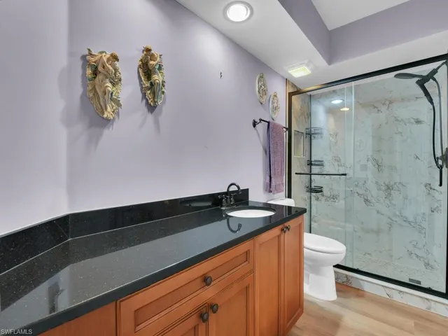 Bathroom featuring a marble finish shower, vanity, toilet, and wood finished floors