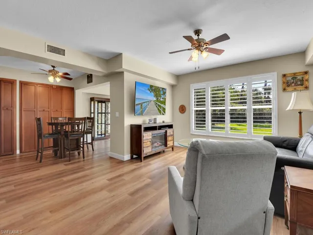 Living room with a wealth of natural light, visible vents, ceiling fan, and light wood finished floors