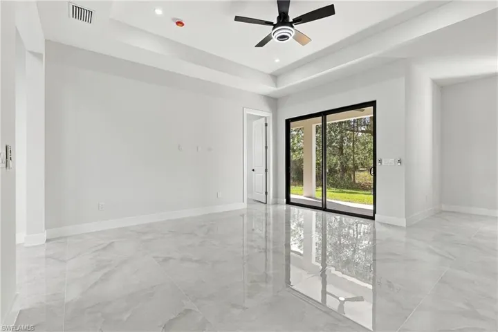 Spacious interior featuring a tray ceiling, ceiling fan with integrated lighting, and polished tile flooring
