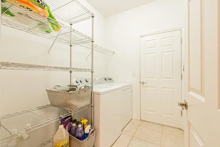 Washroom featuring independent washer and dryer and light tile patterned flooring