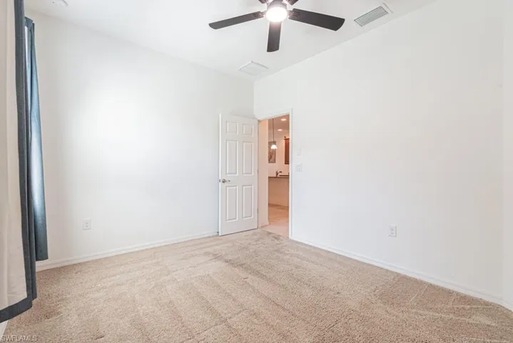 Carpeted guest bedroom with a ceiling fan and baseboards