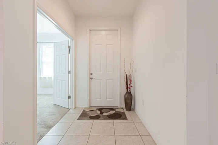 Hallway featuring light tile patterned floors, baseboards, and light carpet