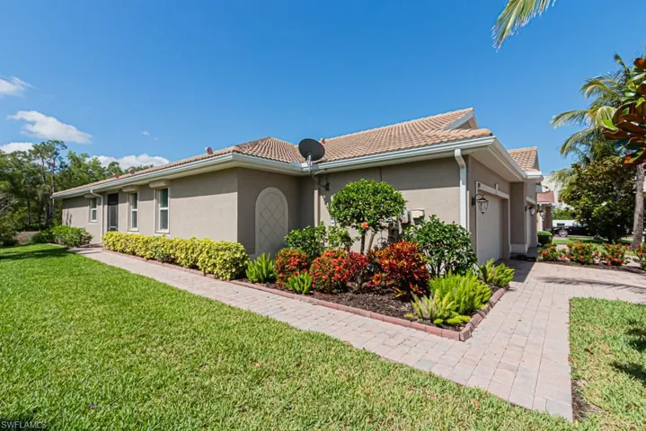 View of home's exterior garage, stucco siding, a tiled roof, and a lawn