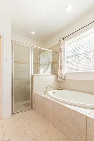 Bathroom with tile patterned flooring, a shower stall, a garden tub, and recessed lighting