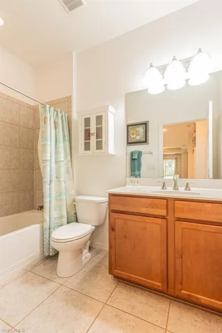 Bathroom with toilet, tile patterned flooring, vanity, and shower / bathtub combination with curtain