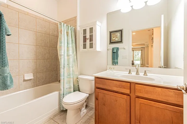 Bathroom with tile patterned floors, toilet, vanity, and shower / bathtub combination with curtain