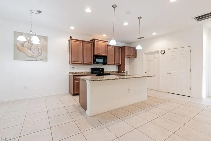 Kitchen featuring black appliances, a sink, light tile patterned floors, recessed lighting, and light stone countertops