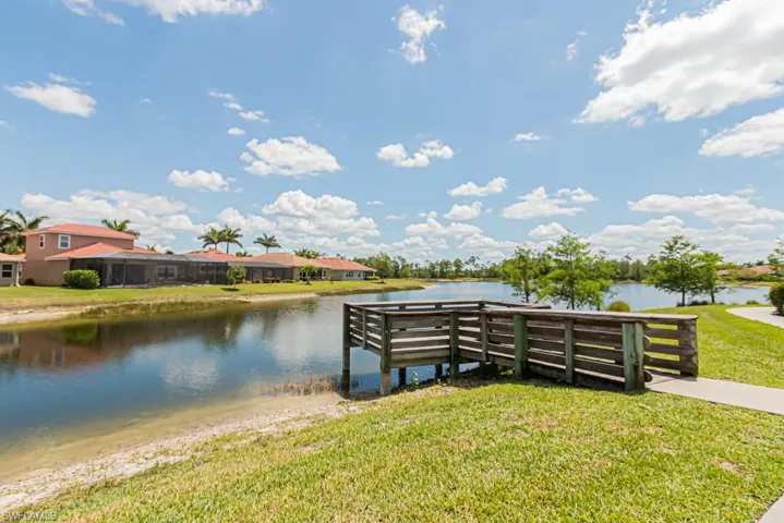 Dock featuring a water view, a lawn, and a residential view
