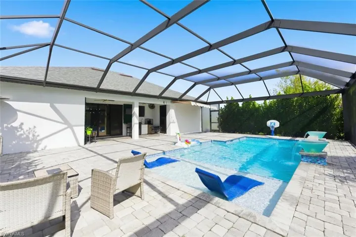 Swimming pool featuring glass enclosure, a sunroom, and a patio area