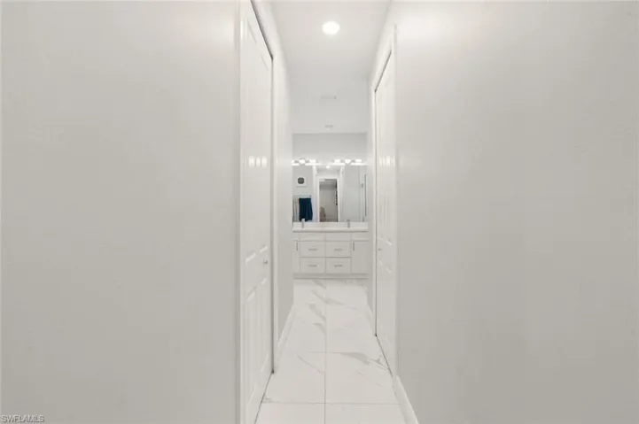 Hall with light marble finish floors and recessed lighting