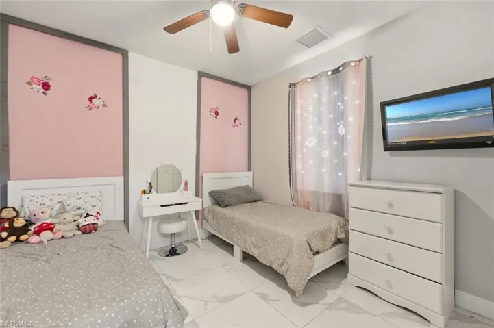 Bedroom featuring light marble finish floors and a ceiling fan
