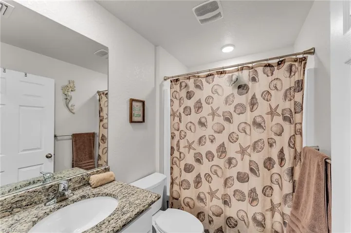 Bathroom with vanity, curtained shower, and toilet