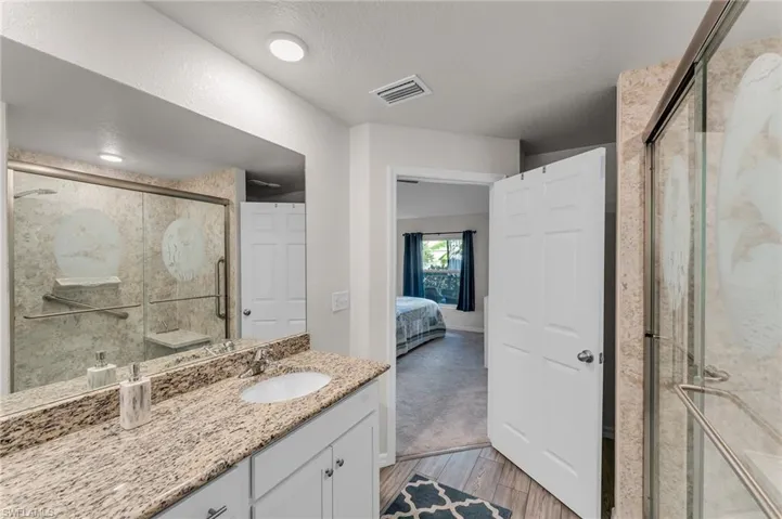 Bathroom featuring vanity, wood-type flooring, a textured ceiling, and an enclosed shower
