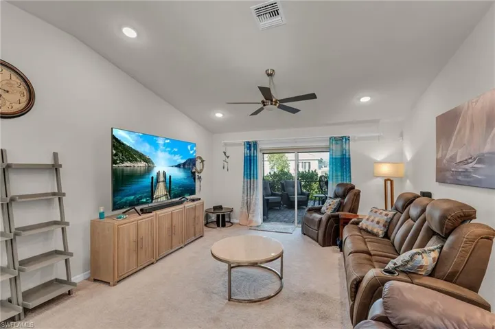 Carpeted living room featuring vaulted ceiling and ceiling fan