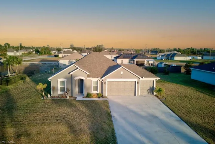 View of front of property with a garage and a yard