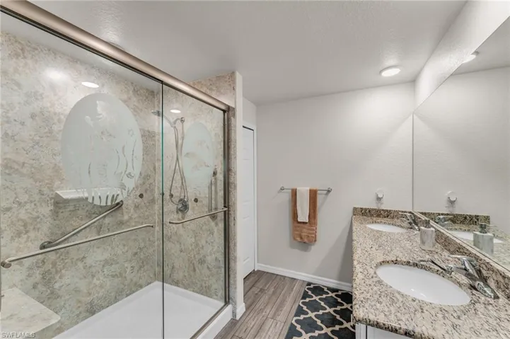 Bathroom with a textured ceiling, vanity, hardwood / wood-style flooring, and walk in shower