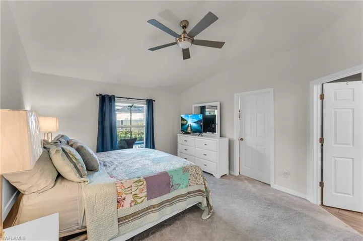Bedroom featuring ceiling fan, light colored carpet, and vaulted ceiling