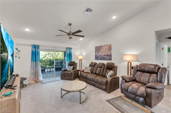 Living room featuring ceiling fan, light carpet, and vaulted ceiling