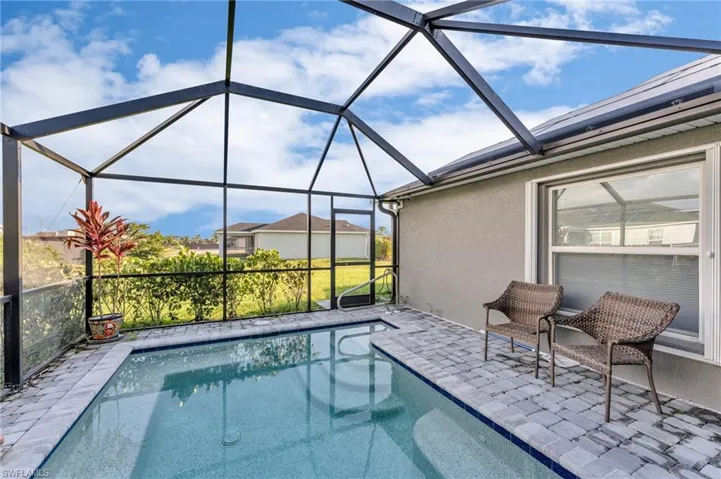 View of swimming pool featuring glass enclosure and a patio area