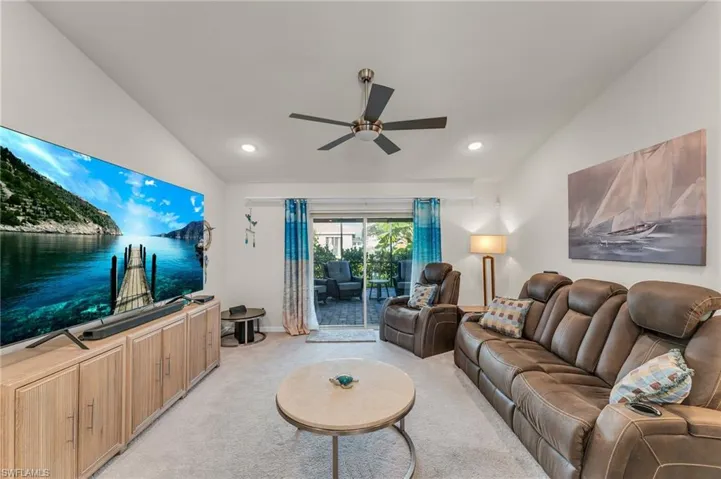 Living room featuring ceiling fan, light carpet, and vaulted ceiling
