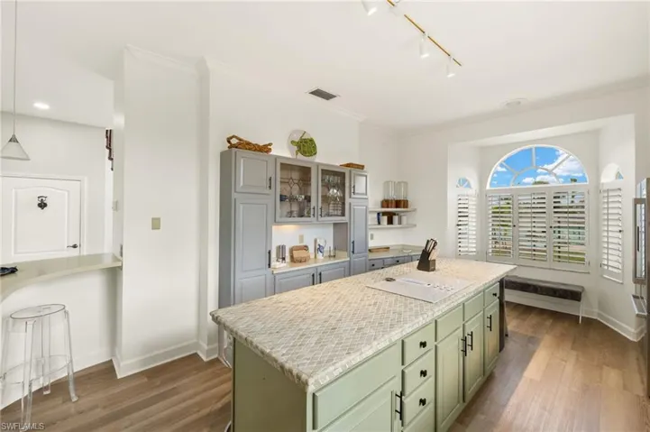 Kitchen featuring open shelves, green cabinets, a kitchen island, light wood-style flooring, and crown molding