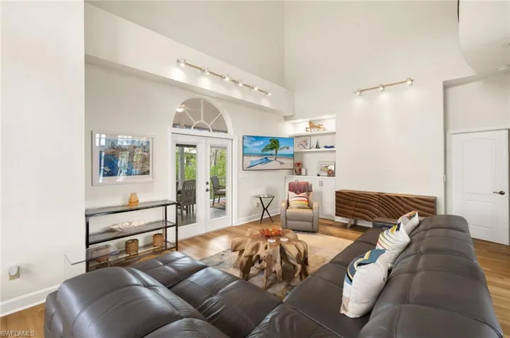 Living area with a towering ceiling, french doors, and wood finished floors