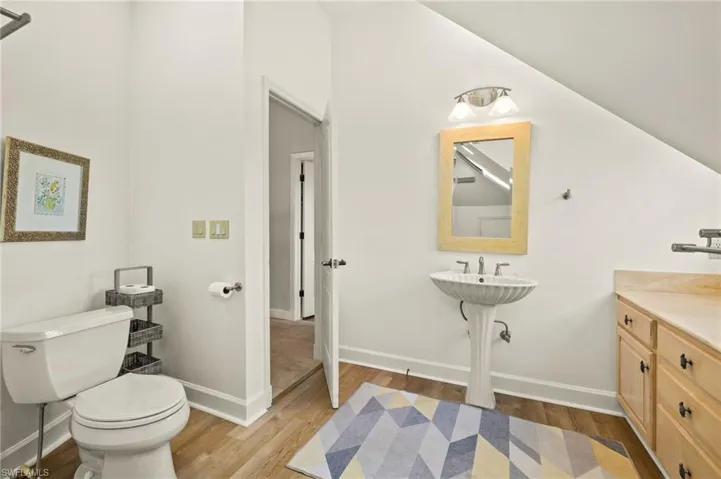 Guest bathroom with dark wood-style flooring and vaulted ceiling