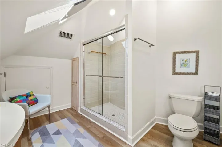 Guest bathroom with a shower stall, wood finished floors, and lofted ceiling