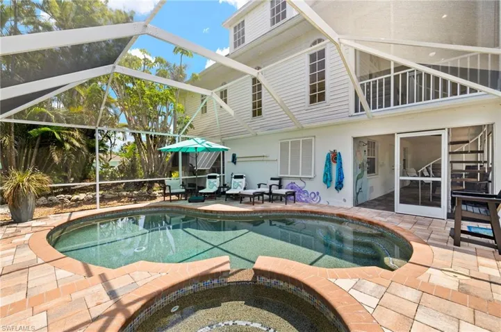 View of pool with a patio area, lanai, glass enclosure, and a pool with connected hot tub