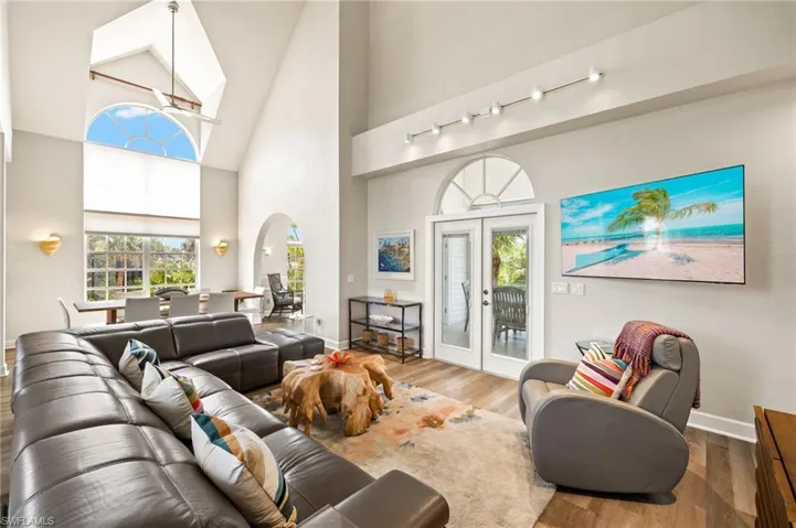 Living room featuring high vaulted ceiling, french doors, plenty of natural light, arched walkways, and wood finished floors