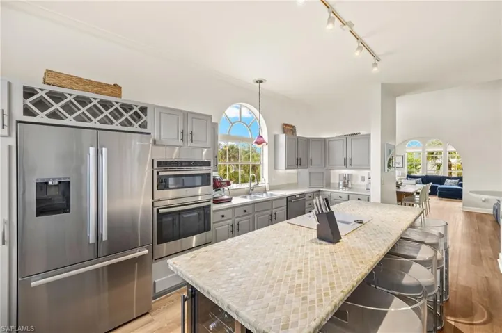 Kitchen featuring gray cabinets, stainless steel appliances, light wood finished floors, and a kitchen bar