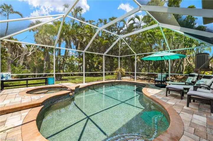 View of pool with a lanai, a pool with connected hot tub