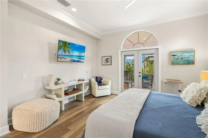 Primary bedroom with french doors, crown molding, wood finished floors, access to outside, and recessed lighting