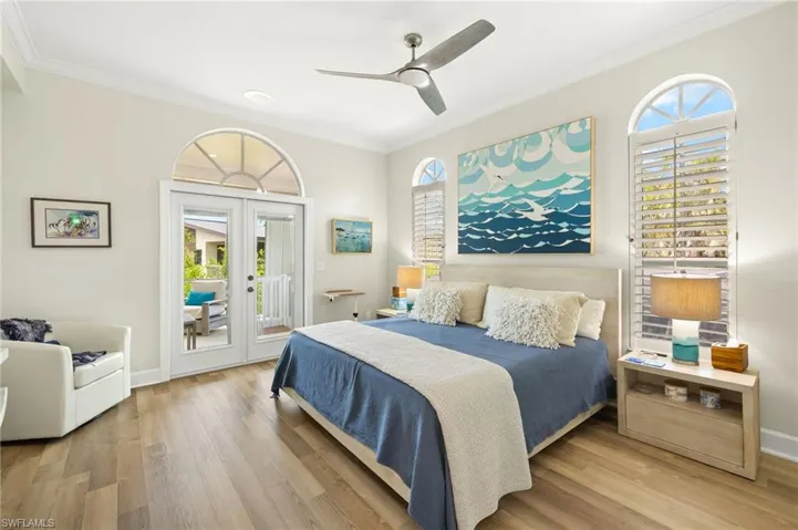 Primary bedroom featuring french doors, access to exterior, light wood finished floors, ceiling fan, and crown molding
