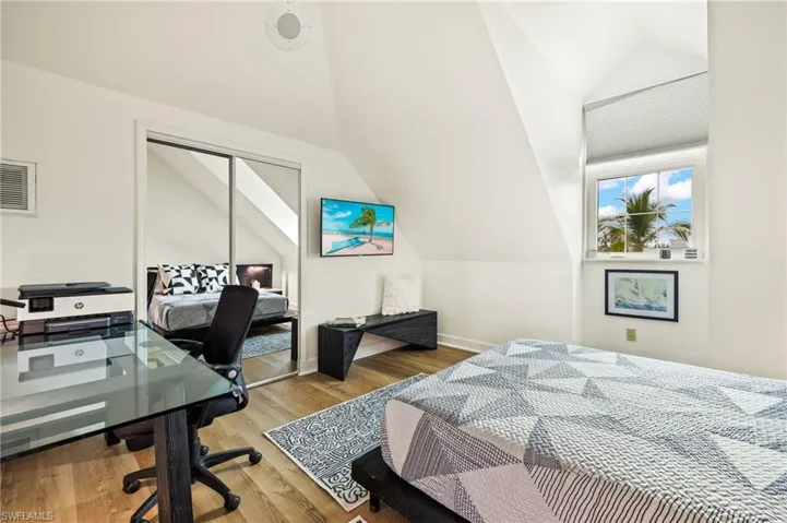 Guest bedroom with vaulted ceiling, an office area, wood finished floors, and a closet