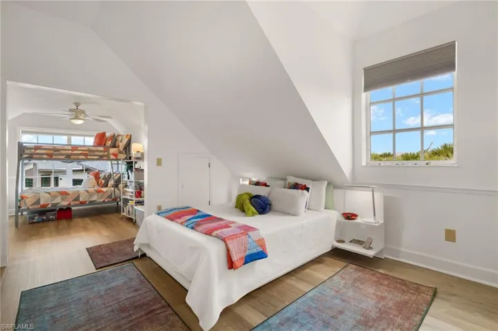 Oversized guest bedroom featuring light wood-type flooring, a ceiling fan, and vaulted ceiling