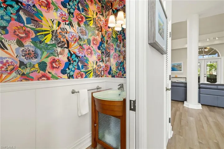 Guest bathroom with vanity, wainscoting, wood finished floors, french doors, and a decorative wall