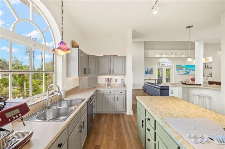 Kitchen featuring white electric stovetop, dark wood finished floors, hanging light fixtures, and healthy amount of natural light