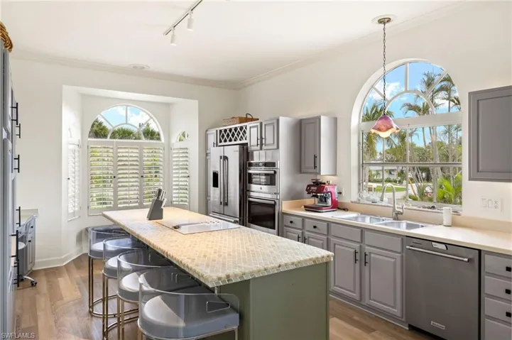 Kitchen featuring gray cabinetry, stainless steel appliances, a breakfast bar area, a kitchen island, and track lighting