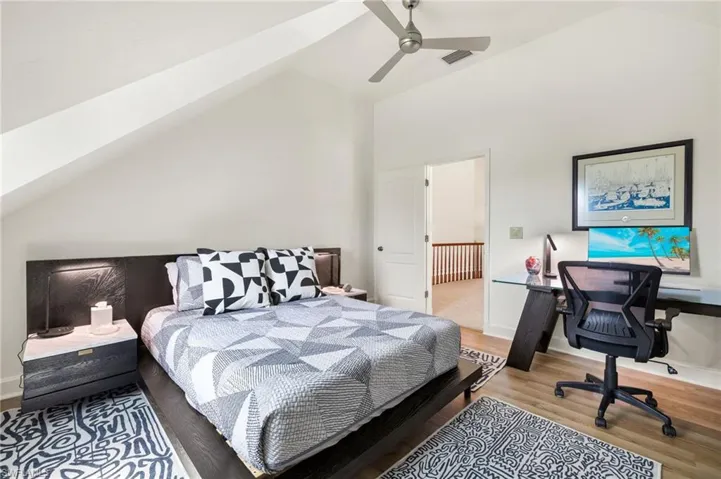 Guest bedroom with light wood-style flooring, a desk, ceiling fan, and high vaulted ceiling