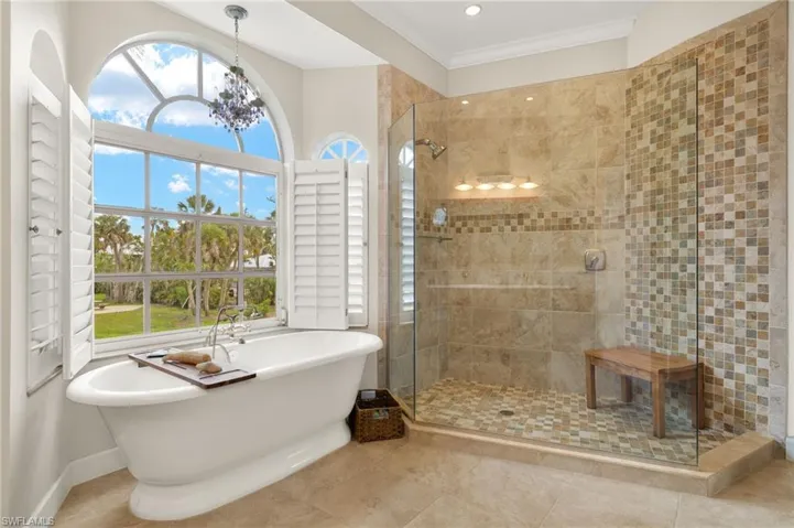 Primary bath featuring a soaking tub, a tile shower, a chandelier, and tile patterned floors